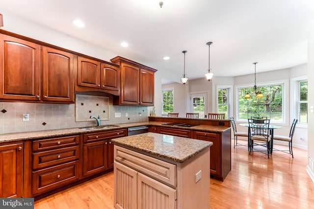 kitchen featuring light wood-type flooring, decorative light fixtures, a kitchen island, and decorative backsplash