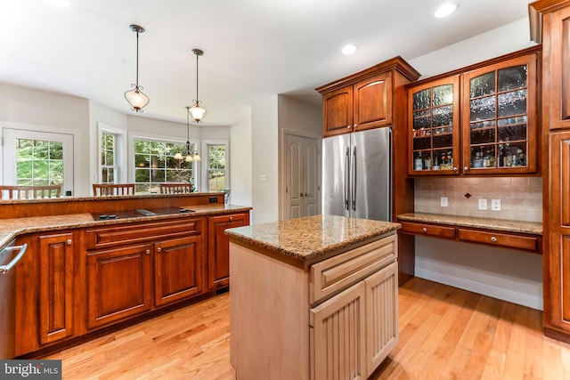 kitchen featuring light hardwood / wood-style flooring, decorative backsplash, a kitchen island, and appliances with stainless steel finishes