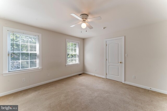 carpeted spare room featuring ceiling fan