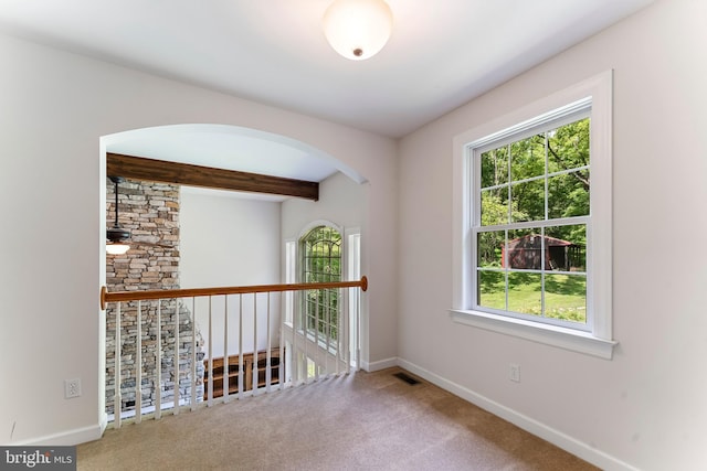 unfurnished room with beamed ceiling and carpet flooring