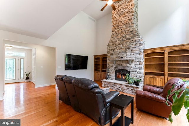 living room featuring ceiling fan, wood-type flooring, a fireplace, and high vaulted ceiling