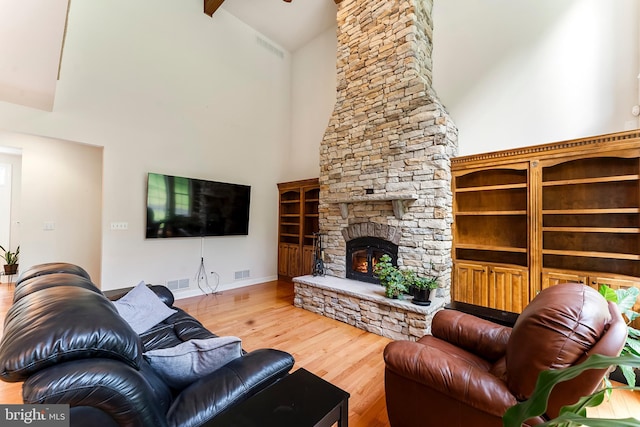 living room featuring wood-type flooring, a stone fireplace, and high vaulted ceiling