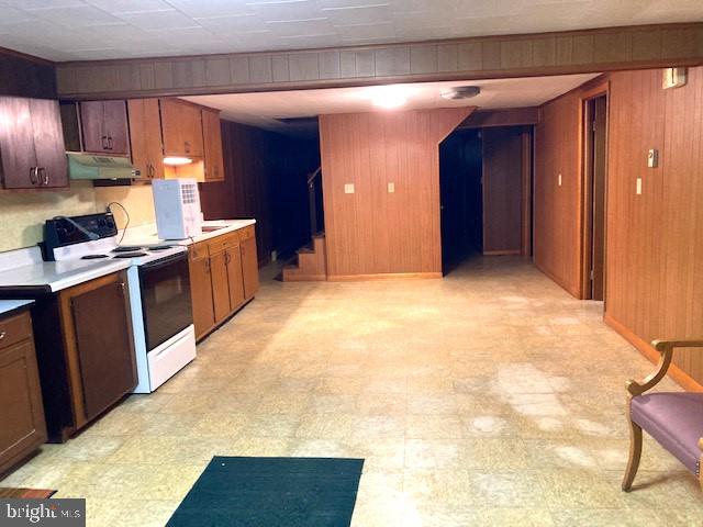 kitchen with wood walls, white range with electric stovetop, and light tile patterned floors