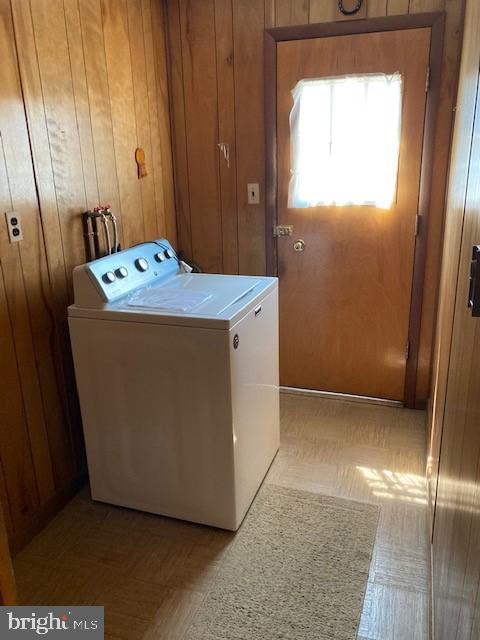 washroom with washer / dryer and wooden walls