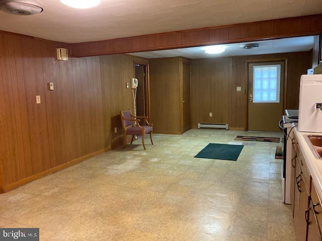 interior space with wood walls, light tile patterned flooring, and baseboard heating