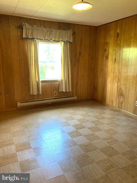 spare room featuring a baseboard radiator and wooden walls