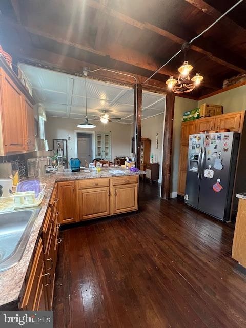 kitchen with kitchen peninsula, decorative light fixtures, dark wood-type flooring, stainless steel fridge with ice dispenser, and ceiling fan with notable chandelier