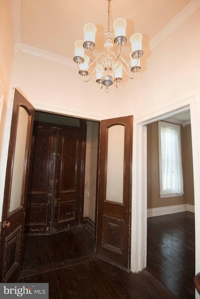 interior space with an inviting chandelier, ornamental molding, and dark wood-type flooring