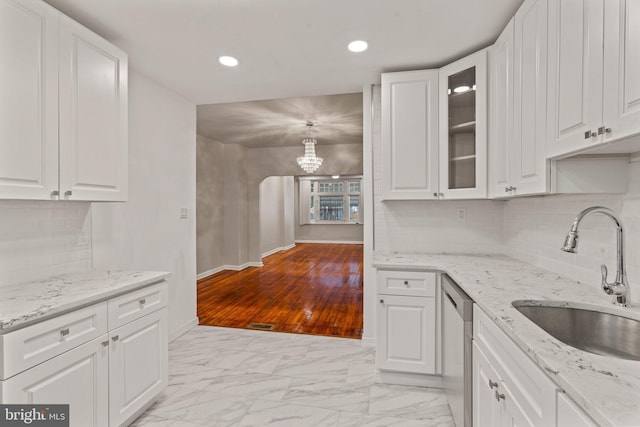 kitchen featuring dishwasher, light stone countertops, sink, and white cabinets