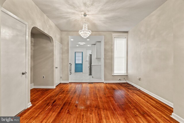 unfurnished room with hardwood / wood-style flooring and an inviting chandelier