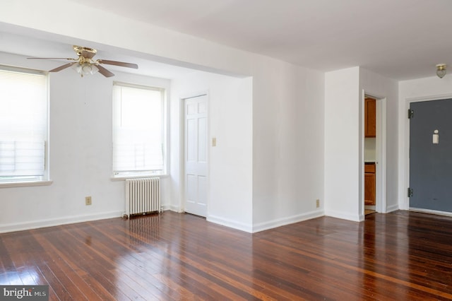 empty room with hardwood / wood-style floors, radiator heating unit, baseboards, and ceiling fan