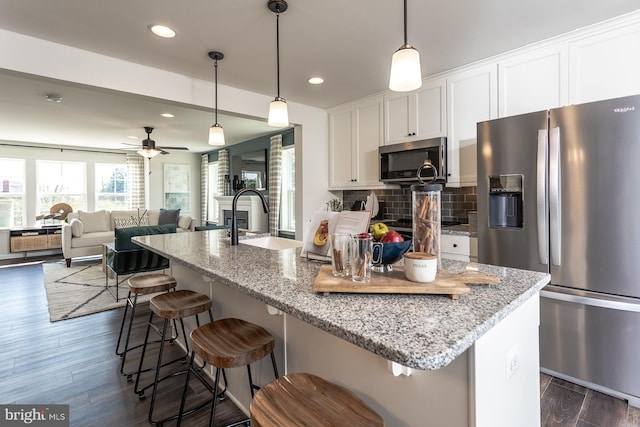 kitchen with white cabinetry, stainless steel appliances, sink, dark hardwood / wood-style floors, and backsplash