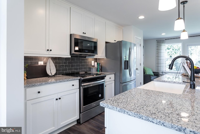 kitchen with white cabinetry, dark hardwood / wood-style flooring, light stone counters, appliances with stainless steel finishes, and backsplash