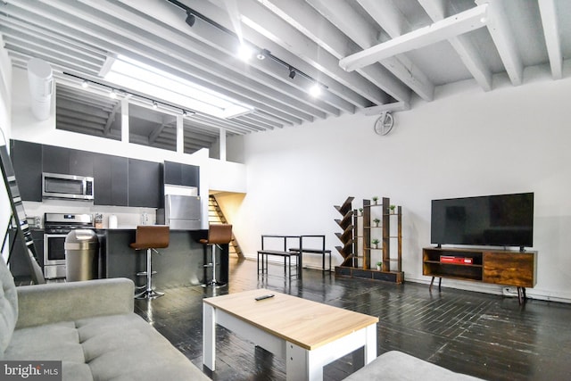 living room with beamed ceiling, dark hardwood / wood-style flooring, and a high ceiling