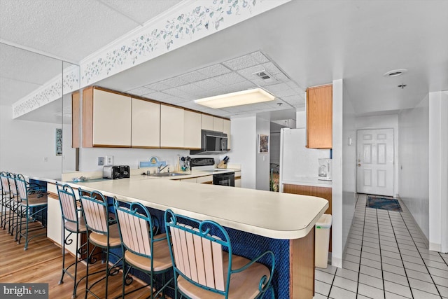 kitchen featuring electric range oven, a kitchen breakfast bar, and kitchen peninsula