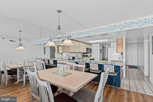 dining room with light hardwood / wood-style floors and a textured ceiling