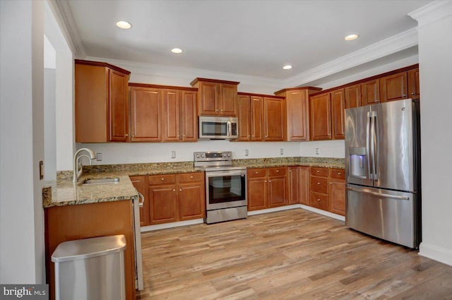 kitchen featuring sink, light hardwood / wood-style flooring, stainless steel appliances, and light stone counters