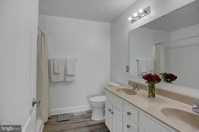 full bathroom featuring toilet, double sink vanity, hardwood / wood-style floors, and shower / bath combination with curtain