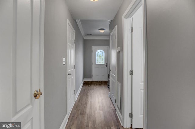 hallway featuring wood-type flooring and ornamental molding