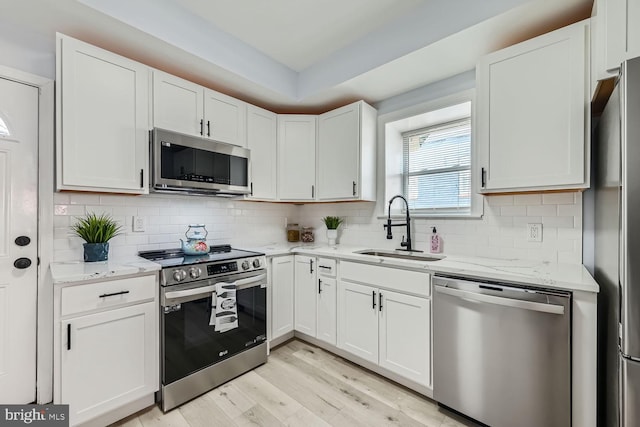 kitchen featuring white cabinetry, sink, light stone counters, and stainless steel appliances