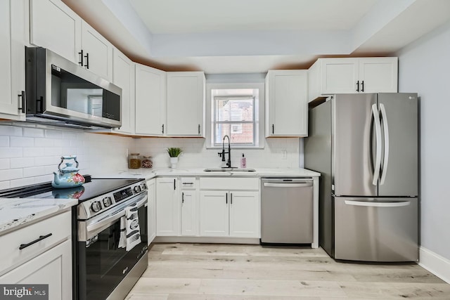 kitchen with white cabinetry, sink, decorative backsplash, light stone counters, and stainless steel appliances