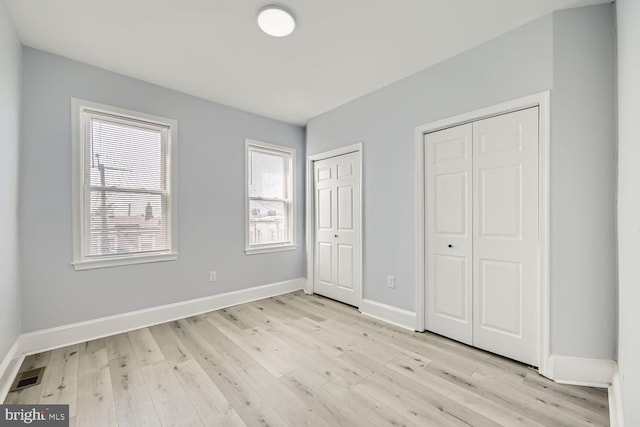 unfurnished bedroom with multiple closets and light hardwood / wood-style floors