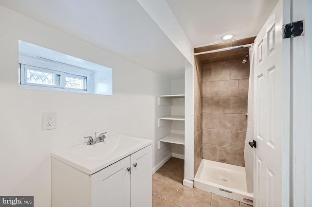 bathroom featuring tile patterned flooring, vanity, and a tile shower