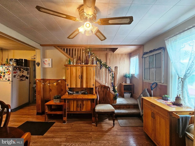 sitting room with ceiling fan, wood-type flooring, and wood walls