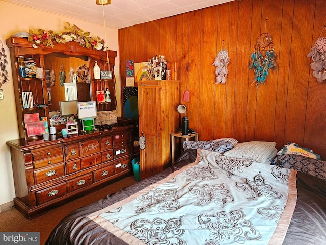 carpeted bedroom featuring wooden walls