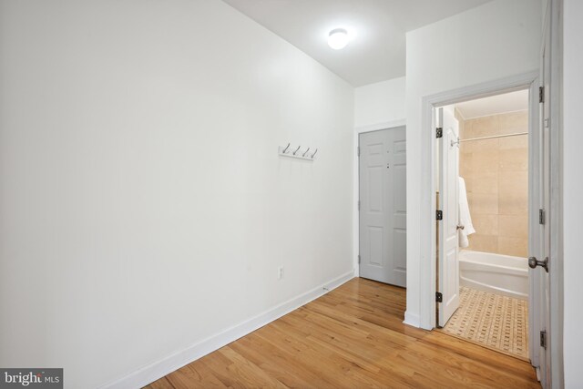 unfurnished bedroom featuring ensuite bathroom and light hardwood / wood-style flooring