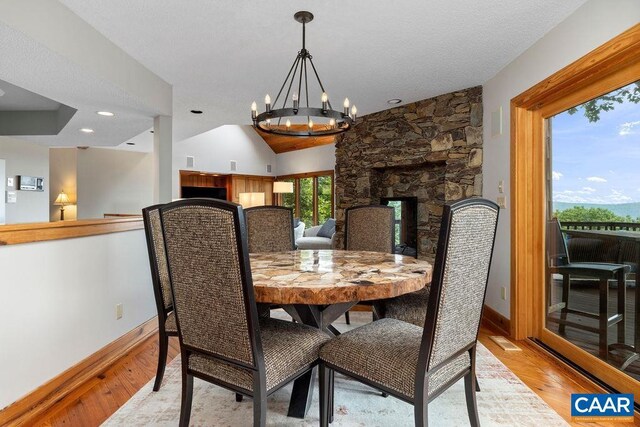 dining space featuring light hardwood / wood-style flooring, an inviting chandelier, and vaulted ceiling