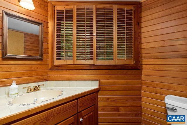 bathroom with vanity, toilet, and wood walls