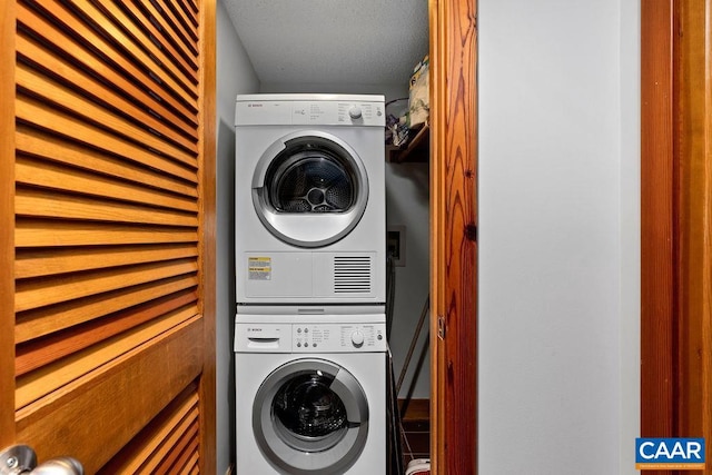 clothes washing area with a textured ceiling and stacked washing maching and dryer