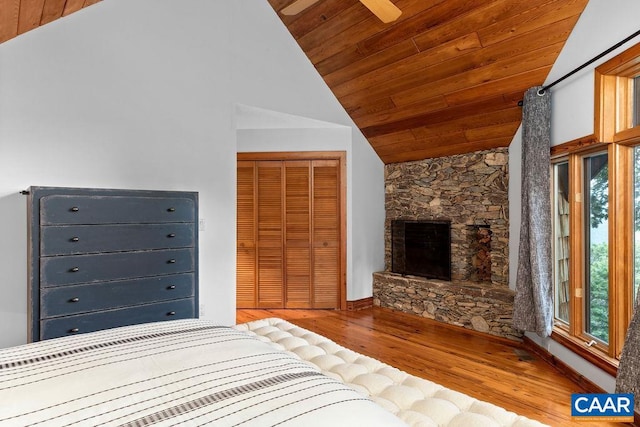 unfurnished bedroom featuring wood ceiling, a stone fireplace, hardwood / wood-style flooring, and a closet