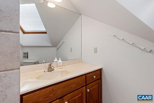 bathroom featuring vanity, toilet, and vaulted ceiling