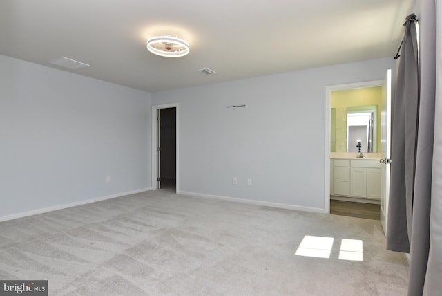 unfurnished bedroom featuring light colored carpet and ensuite bath