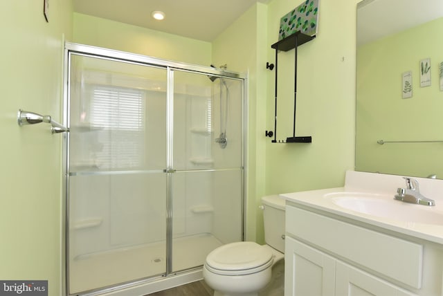 bathroom with vanity, a shower with door, and toilet