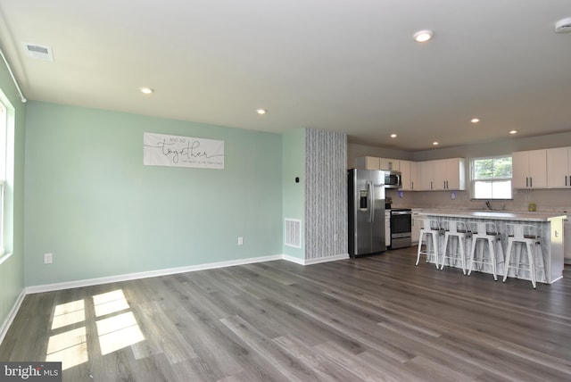 kitchen featuring a kitchen island, appliances with stainless steel finishes, white cabinets, a kitchen bar, and light hardwood / wood-style flooring