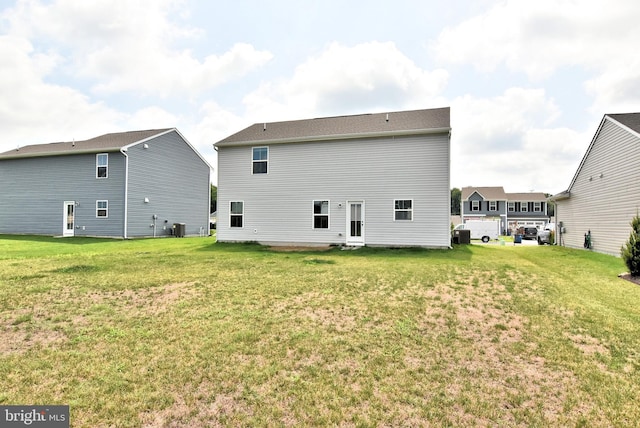 rear view of property featuring cooling unit and a yard