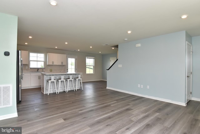 kitchen featuring stainless steel refrigerator, white cabinets, a kitchen breakfast bar, a center island, and plenty of natural light