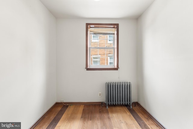 spare room with radiator heating unit and hardwood / wood-style floors