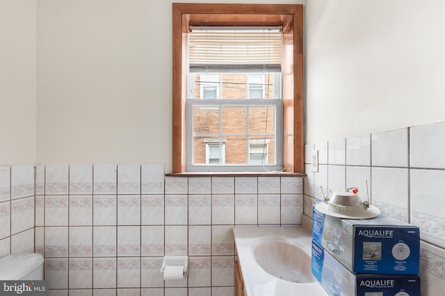 full bathroom featuring tile patterned flooring, tiled shower / bath combo, toilet, vanity, and tile walls