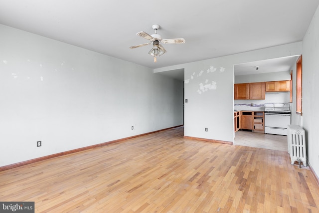 spare room featuring ceiling fan, light hardwood / wood-style flooring, and radiator heating unit