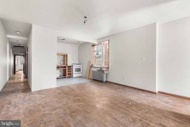 unfurnished living room featuring radiator heating unit, sink, and hardwood / wood-style floors