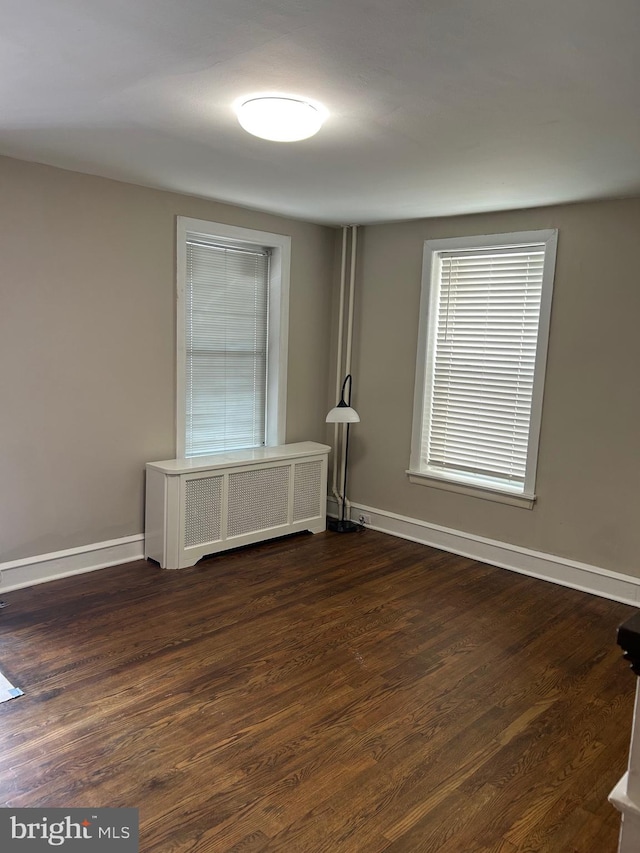 unfurnished room featuring radiator heating unit and hardwood / wood-style floors