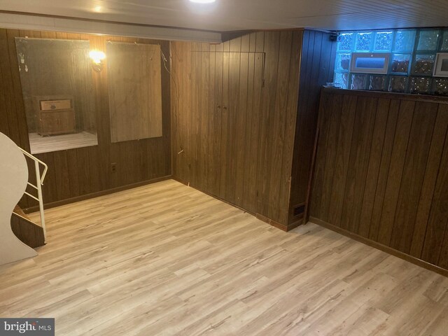 basement featuring wooden walls and light hardwood / wood-style floors