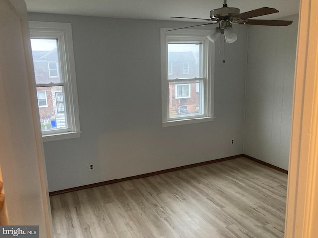 spare room with light hardwood / wood-style flooring, a wealth of natural light, and ceiling fan