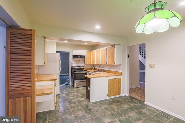 kitchen with electric range, a sink, light countertops, freestanding refrigerator, and decorative backsplash