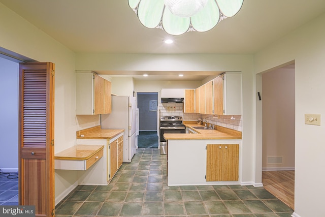 kitchen featuring light countertops, electric range, decorative backsplash, a sink, and under cabinet range hood