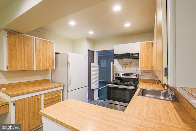 kitchen featuring freestanding refrigerator, a sink, under cabinet range hood, stainless steel range with electric stovetop, and backsplash